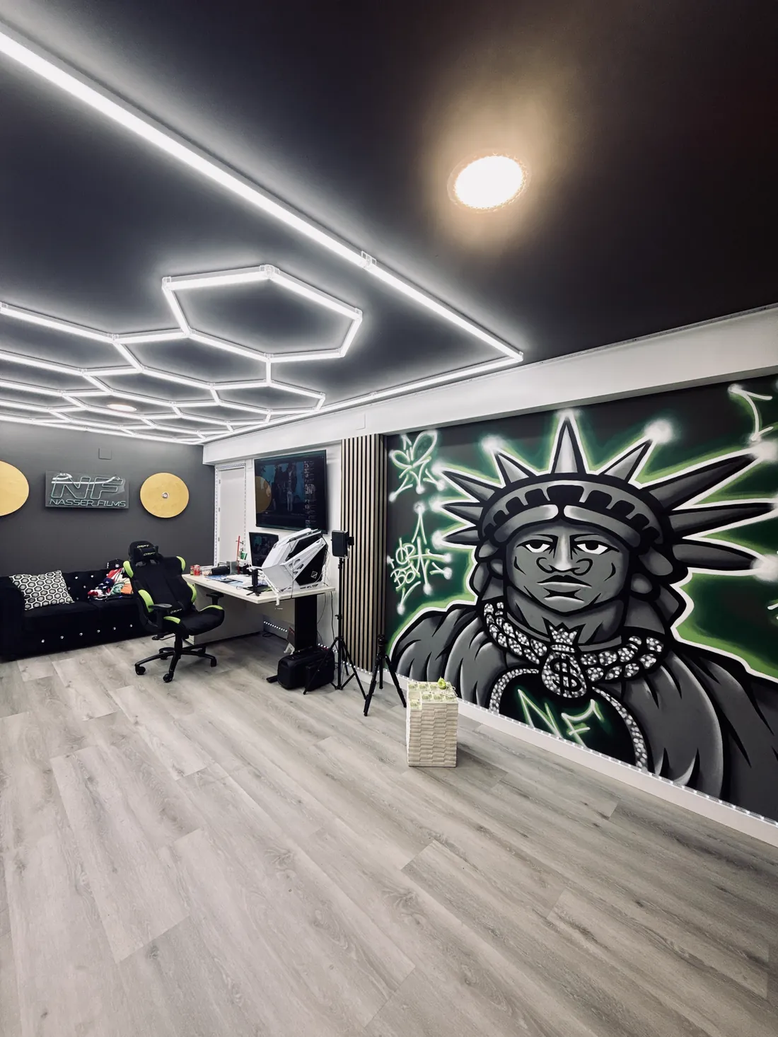 Interior del estudio con techo LED hexagonal, mesa de edición y el mural